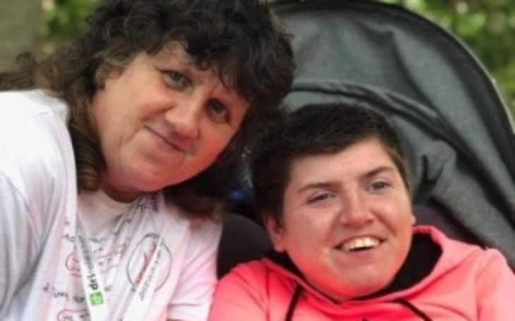 Uśmiechnięta mama z dzieckiem w wózku, spędzają czas na świeżym powietrzu.