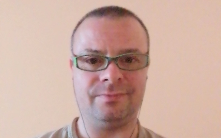 Mężczyzna w okularach, słuchający muzyki przez słuchawki.
