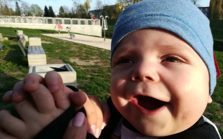 Uśmiechnięte dziecko trzymane na rękach, w parku.