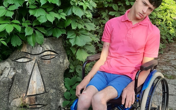 Młody mężczyzna na wózku inwalidzkim obok rzeźby.