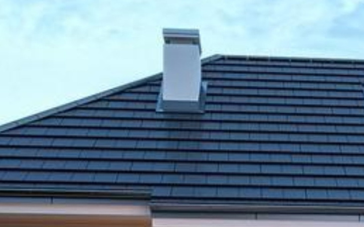 Dach z kominem na tle nieba.