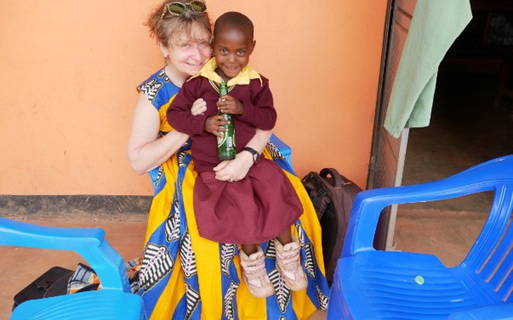 Kobieta trzymająca dziecko na kolanach, oboje uśmiechnięci.