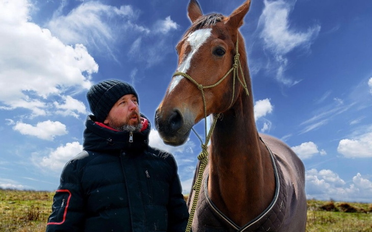 Mężczyzna z koniem na tle nieba, w zimowej scenerii.