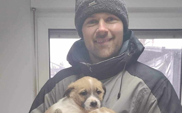 Mężczyzna trzyma szczeniaka w zimowej kurtce.