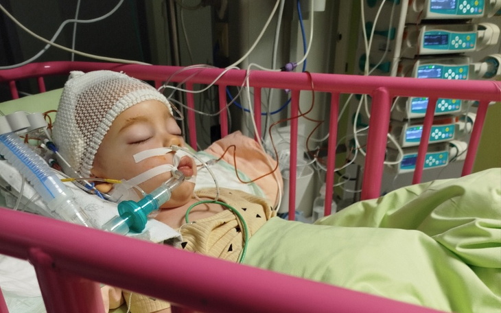 Dziecko w szpitalnym łóżku z podłączonymi urządzeniami.