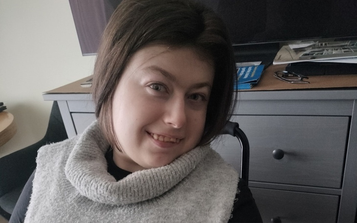 Uśmiechnięta dziewczyna w swetrze, siedząca przy biurku.