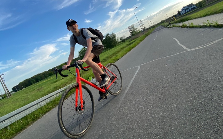 Młody mężczyzna na rowerze, jedzie wzdłuż drogi.