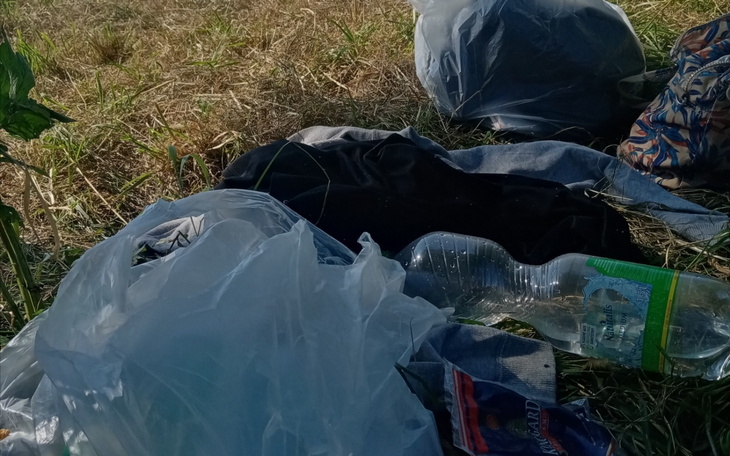 Odpady plastikowe i ubrania porzucone na trawie.