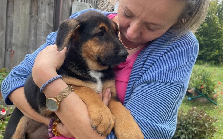 Kobieta trzymająca szczeniaka, oboje wyglądają na szczęśliwych.