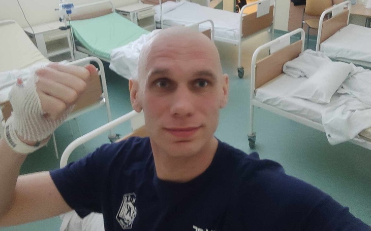 Mężczyzna w szpitalu, uśmiechający się i pokazujący pięść.