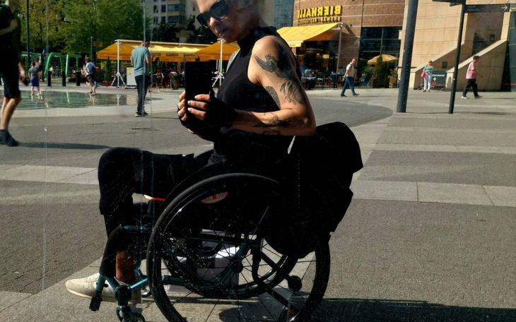 Kobieta na wózku inwalidzkim, selfie w miejskim otoczeniu.