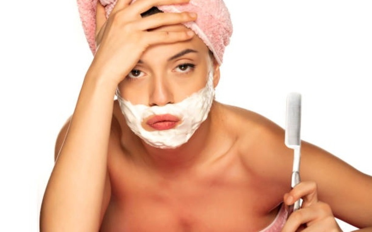 Kobieta z pianką do golenia na twarzy, z ręcznikiem na głowie.