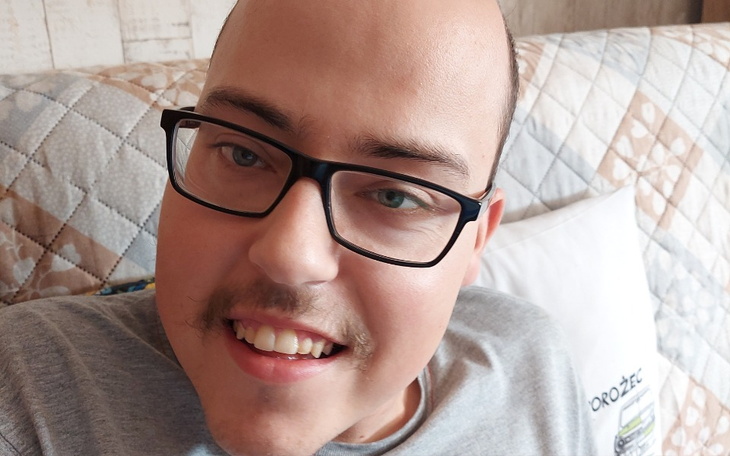 Mężczyzna z uśmiechem, siedzący na kanapie.