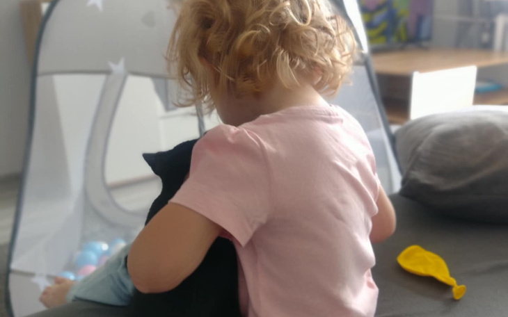 Mała dziewczynka przytulająca czarnego kota w domu.