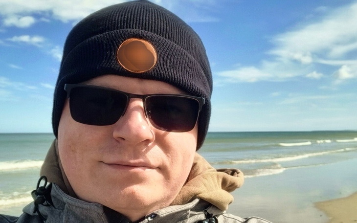 Mężczyzna na plaży w okularach przeciwsłonecznych i czapce.