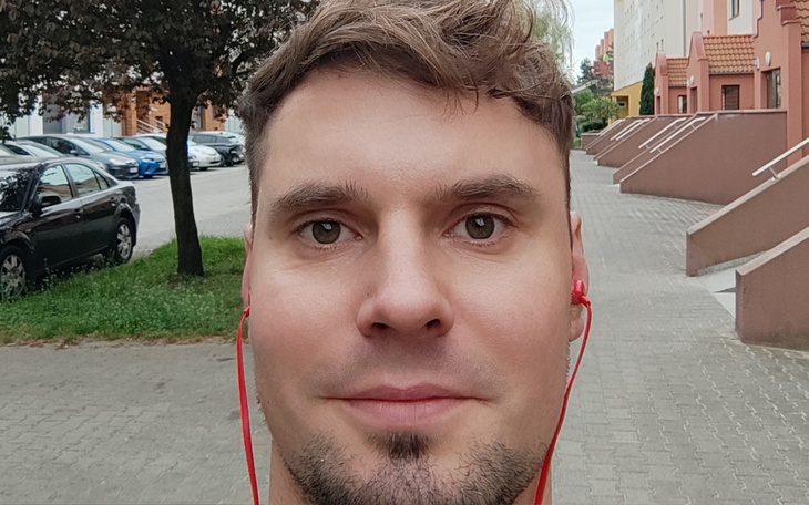 Mężczyzna z słuchawkami spacerujący po osiedlu.