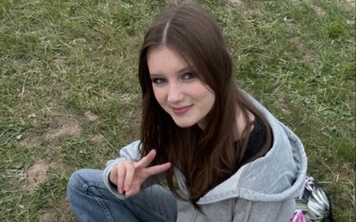 Uśmiechnięta nastolatka siedzi na trawie i pozuje do zdjęcia.