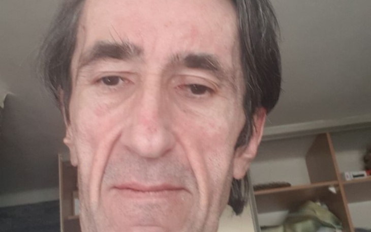 Mężczyzna z zamyślonym wyrazem twarzy, w tle półki.