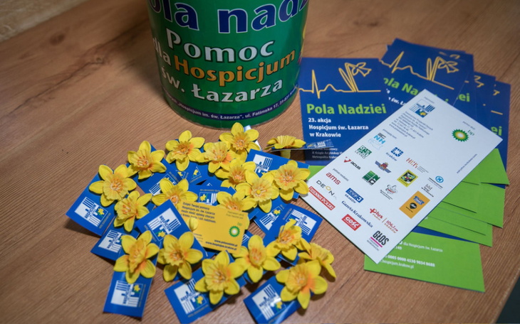 Zbiórka na hospicjum z żółtymi kwiatami i ulotkami.