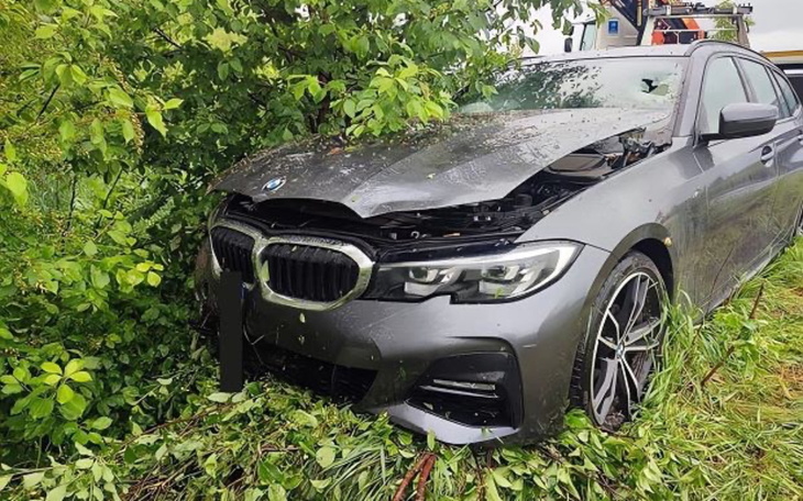 Uszkodzony samochód BMW w zaroślach po wypadku.