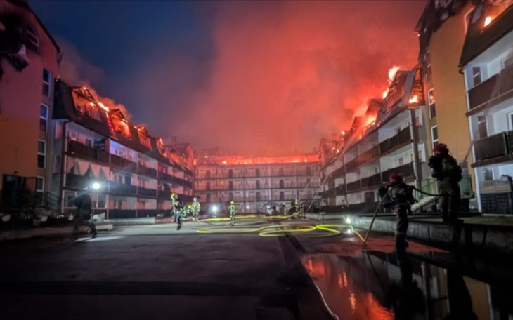Pożar budynku, strażacy walczą z ogniem w nocy.
