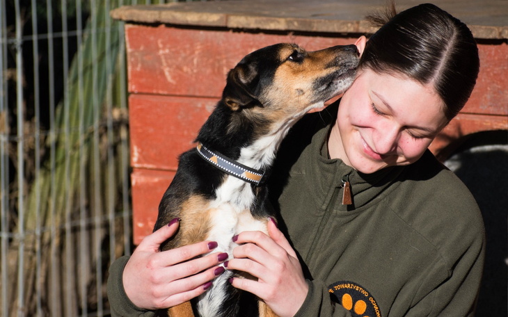 Dziewczynka z uśmiechem przytula psa.