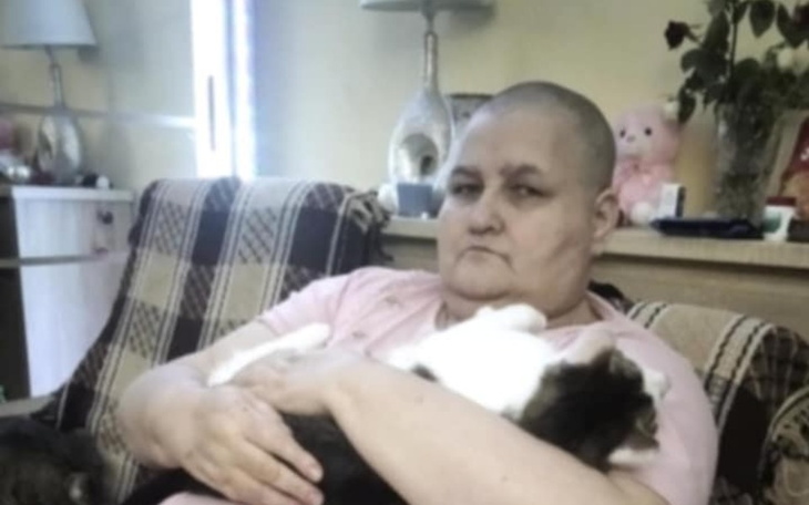 Kobieta z krótkimi włosami, trzymająca kota na kolanach.