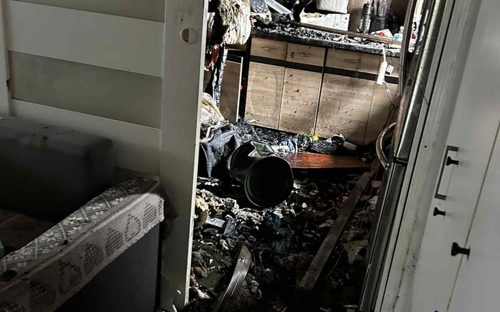 Zniszczona kuchnia po pożarze, z bałaganem i zniszczeniami.