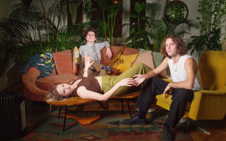 Trójka młodych ludzi w stylowej scenerii z roślinami.