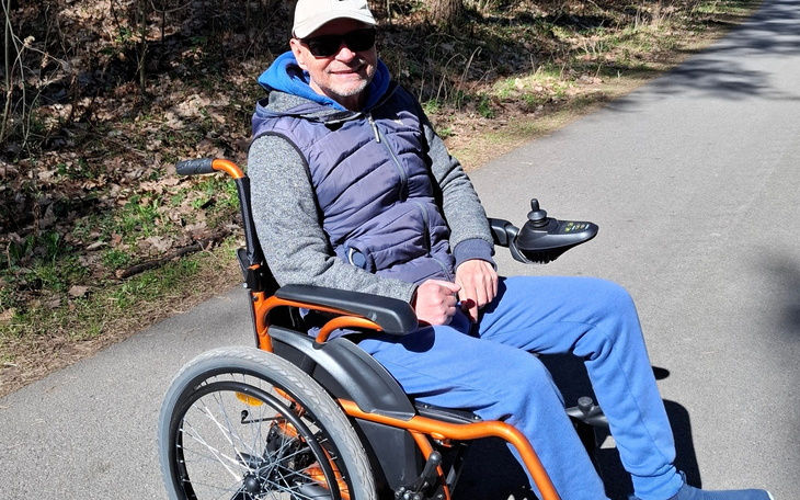Mężczyzna na wózku inwalidzkim, cieszy się wiosennym spacerem.