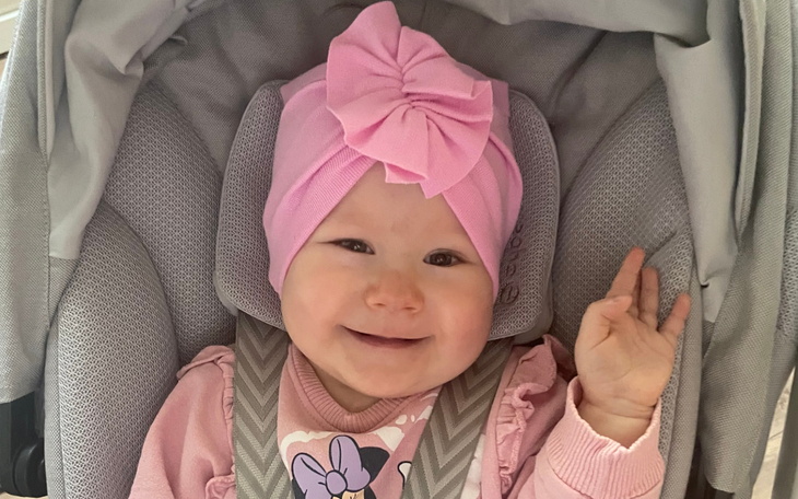 Uśmiechnięta dziewczynka w różowej czapce i ubraniu.