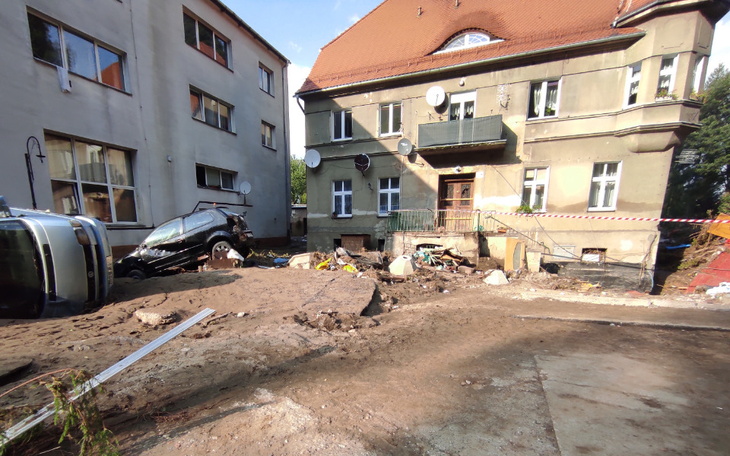 Zniszczony budynek po powodzi, z samochodem w gruzach.