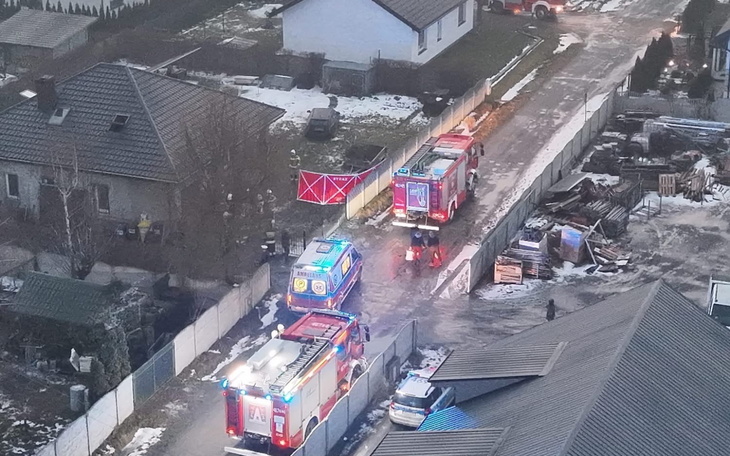 Akcja ratunkowa w miejscowości z widokiem na domy i pojazdy strażackie.