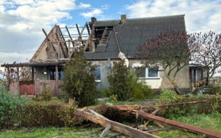 Zniszczony dom z uszkodzonym dachem i otoczeniem.