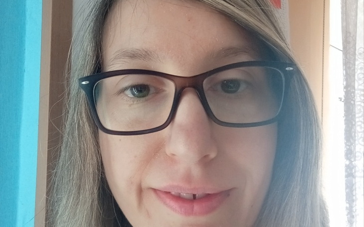 Portret kobiety w okularach, uśmiechającej się do kamery.