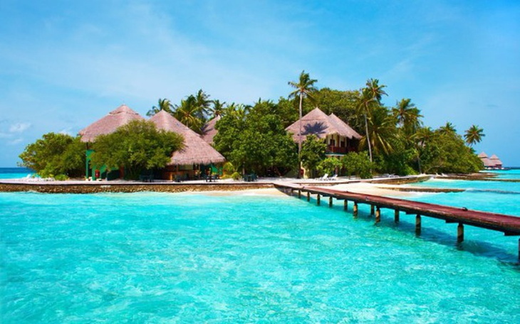 Tropikalna wyspa z palmami i domkami na plaży.