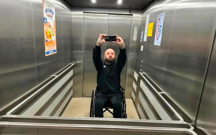 Mężczyzna w wózku inwalidzkim robiący selfie w windzie.