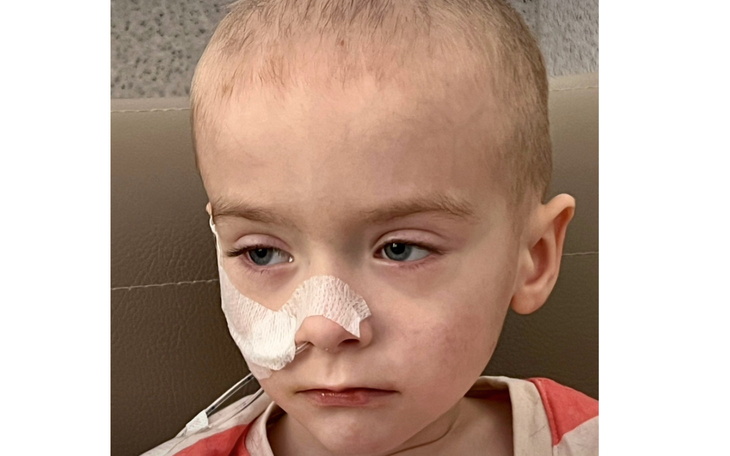 Chłopiec z rurką tlenową w szpitalnym łóżku.