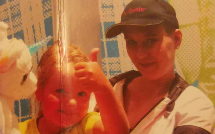 Mama z dzieckiem, oboje uśmiechnięci, na tle kolorowego tła.