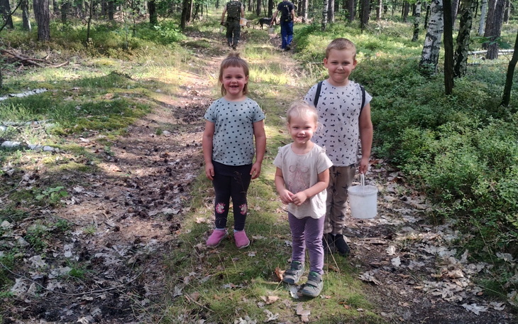 Dzieci bawiące się w lesie, uśmiechnięte i radosne.