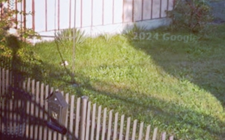 Zielony trawnik z ogrodzeniem i cieniem budynku.