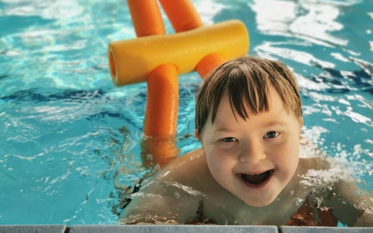 Uśmiechnięty chłopiec bawiący się w basenie z pianką.