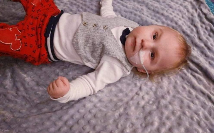 Mały chłopiec leżący na kocyku, z rurką tlenową.