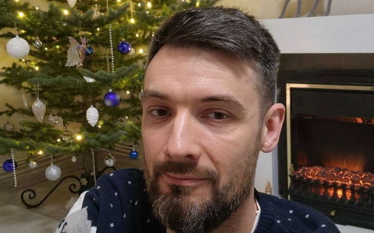 Mężczyzna przed choinką i kominkiem, świąteczna atmosfera