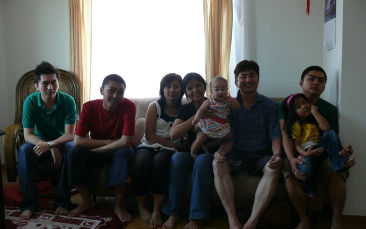 Rodzina pozująca na kanapie, z dzieckiem w ramionach.