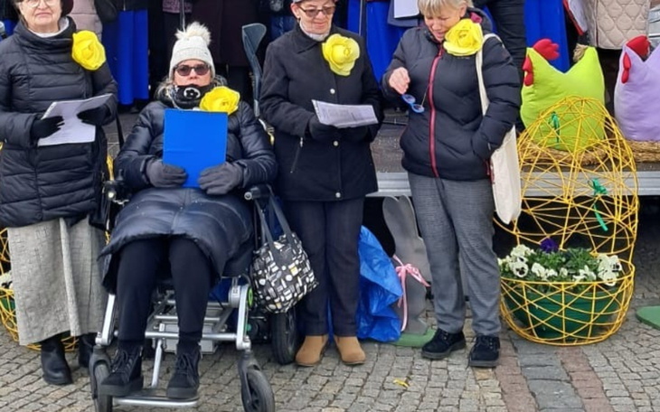 Grupa kobiet w strojach z żółtymi kwiatami.