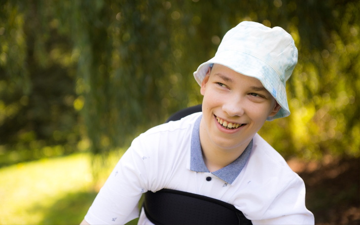 Uśmiechnięty chłopak w kapeluszu, spędzający czas na świeżym powietrzu.