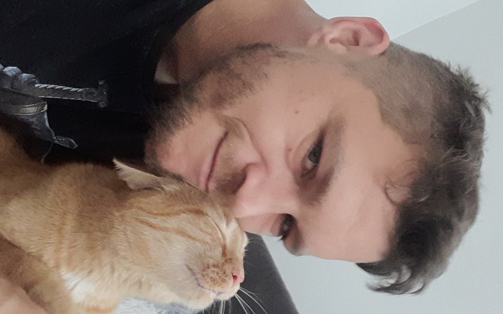 Mężczyzna przytula kota, obaj wyglądają na zrelaksowanych.