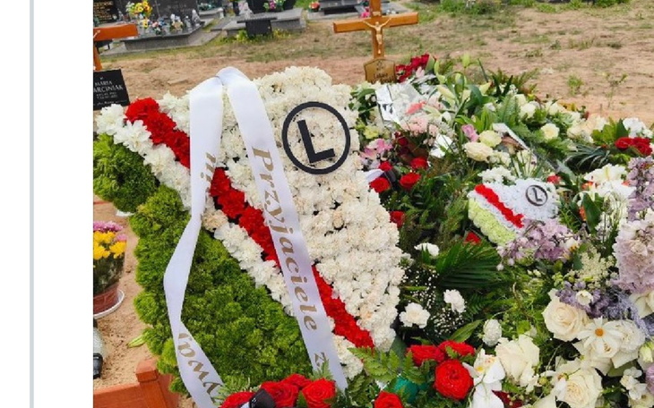 Kwiaty na grobie, z napisem 'Przyjaciele'.