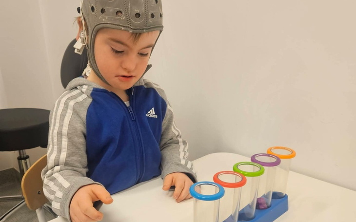 Chłopiec w kasku bawi się kolorowymi probówkami.